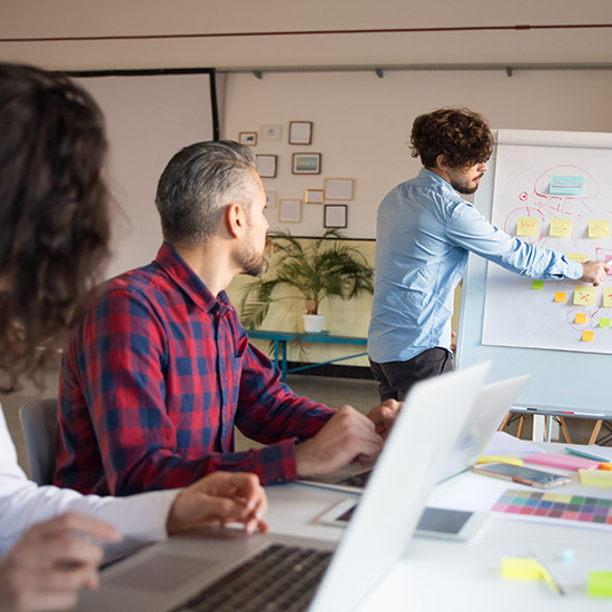 KI Workshop mit Verwaltungsrat. Flipchart mit KI Strategie, Teilnehmer mit Laptops